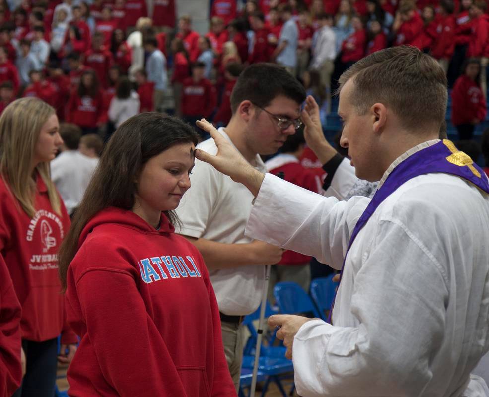 • Charlotte Catholic High School's chaplain, Father Jason Barone, places ashes on the forehead of senior Hannah Daly following a school-wide Lenten Mass Feb. 14. (Photo provided by Joann S. Keane)