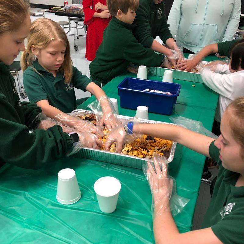 Kindergarten and fifth-grades at St. Patrick School in Charlotte spent a morning during Catholic Schools Week making Snackwell snack bags, which will be sold during lunches for $1, to raise money for the Cross Catholic water project. (Photos via Facebook)