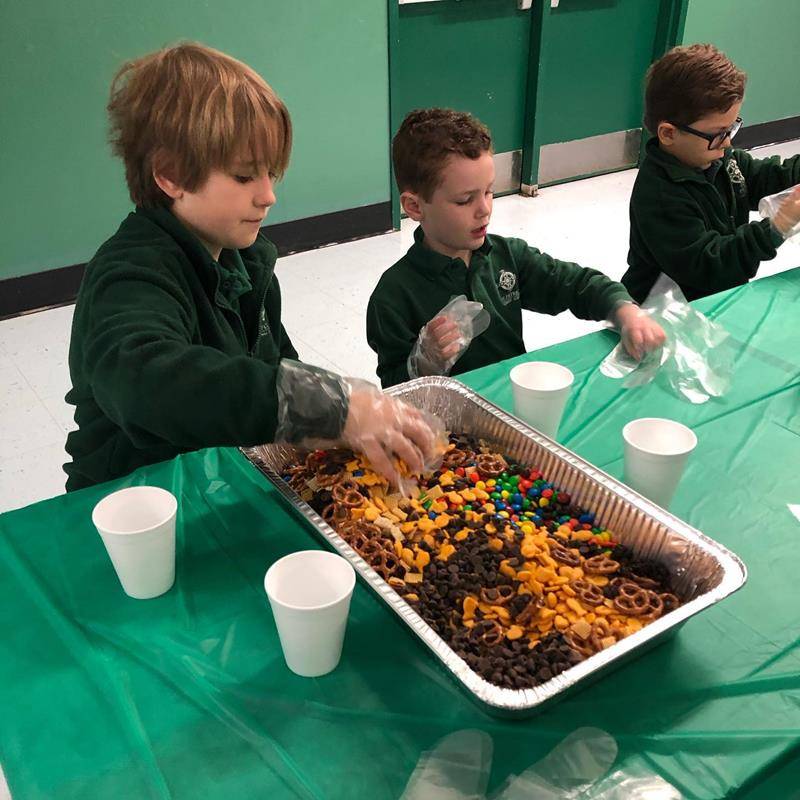 Kindergarten and fifth-grades at St. Patrick School in Charlotte spent a morning during Catholic Schools Week making Snackwell snack bags, which will be sold during lunches for $1, to raise money for the Cross Catholic water project. (Photos via Facebook)