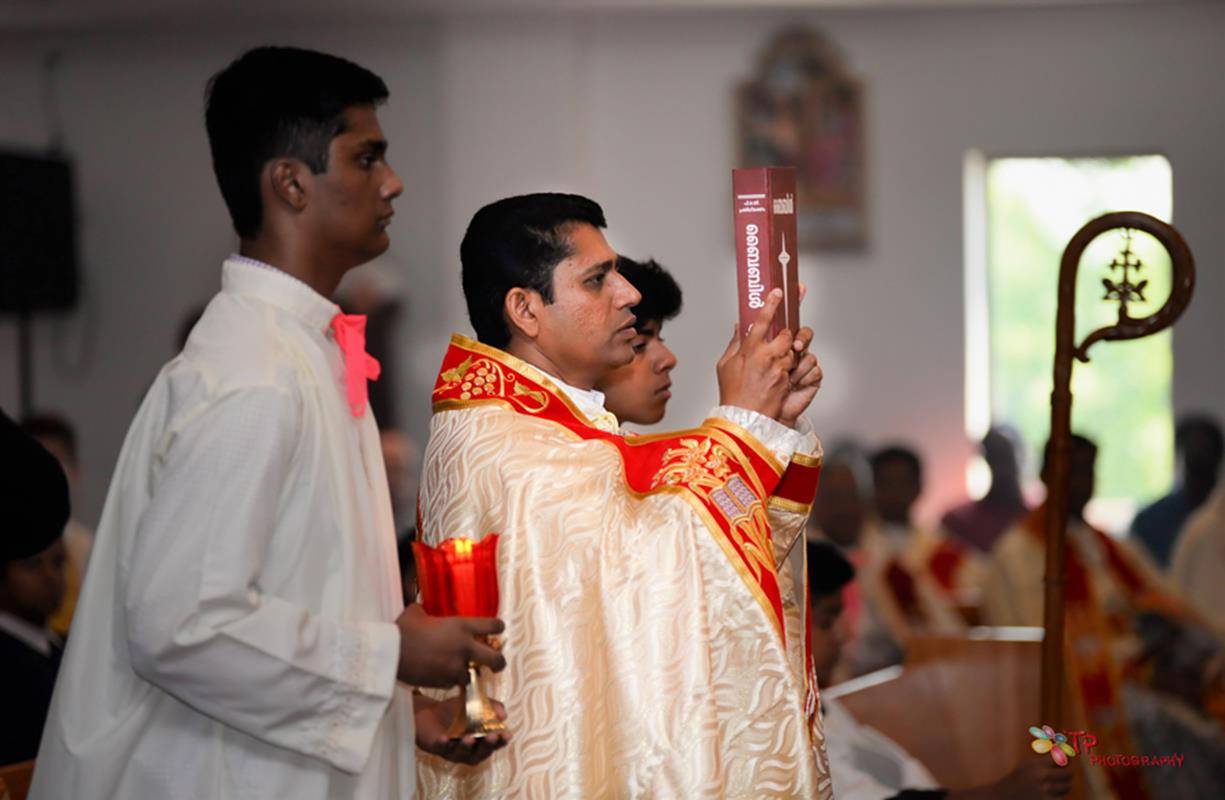 Father Paul Chalissery, pastor of St. Mary's, processes with the Book of the Gospels at Mass.