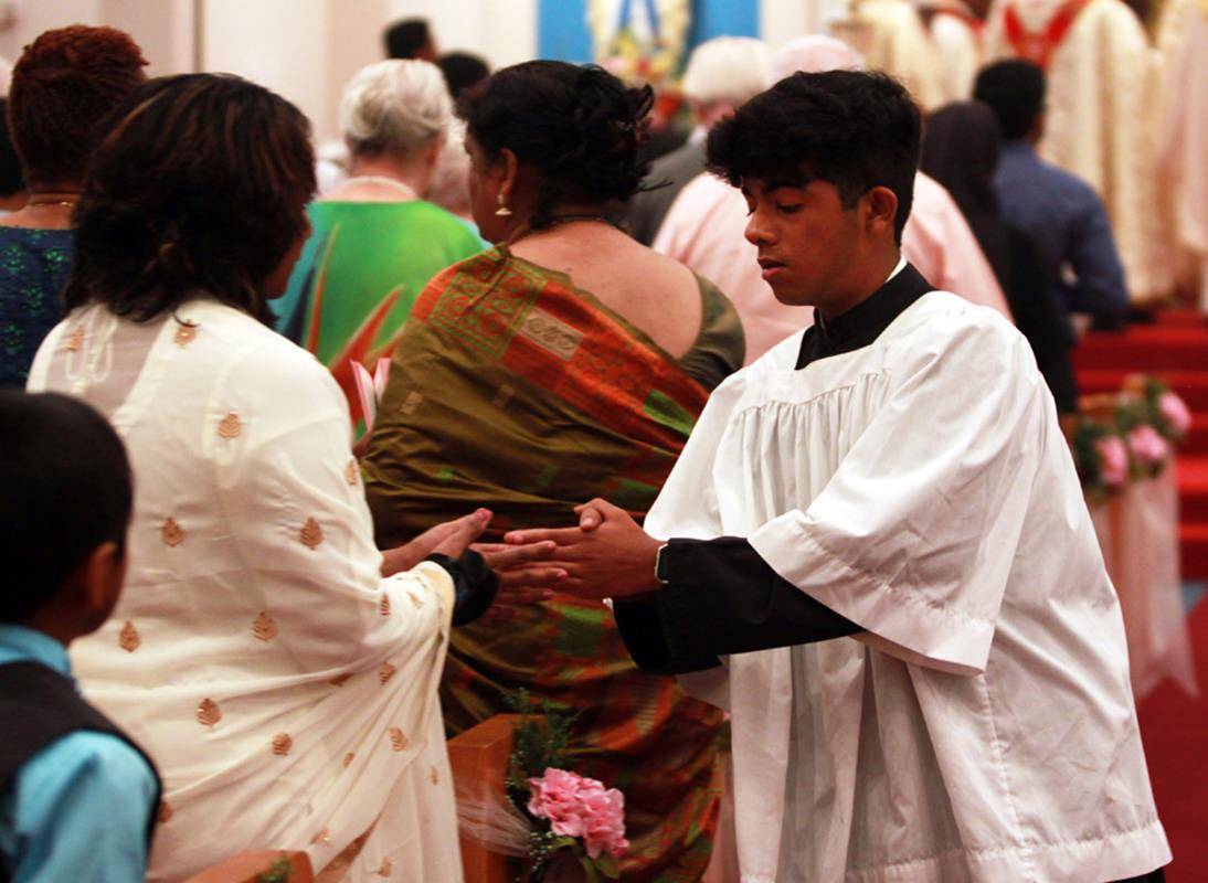 29.	The sign of peace is extended from the priests on the altar down to the acolytes, who then approach the first person in each pew to share the sign of peace. People then share the sign with each other, putting their folded hands in the other person's f