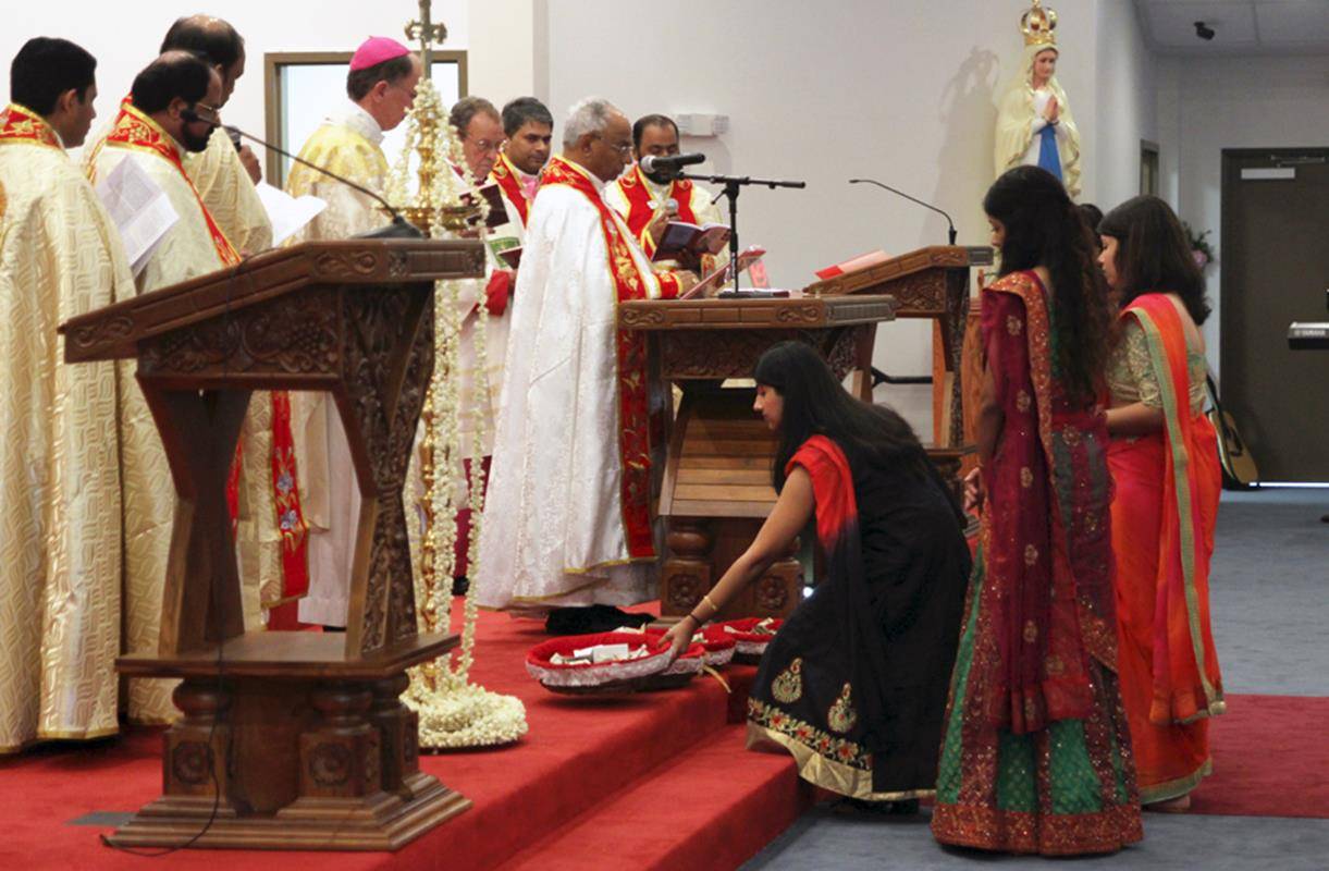 Congregants bring up the offertory collection during Mass.