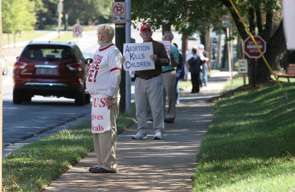 Parishioners of St. Gabriel Church in Charlotte pray with their pastor, Father Frank O'Rourke, along the sidewalk in front of the parish at the corner of Providence and Sharon Amity Roads. (SueAnn Howell, Catholic News Herald)