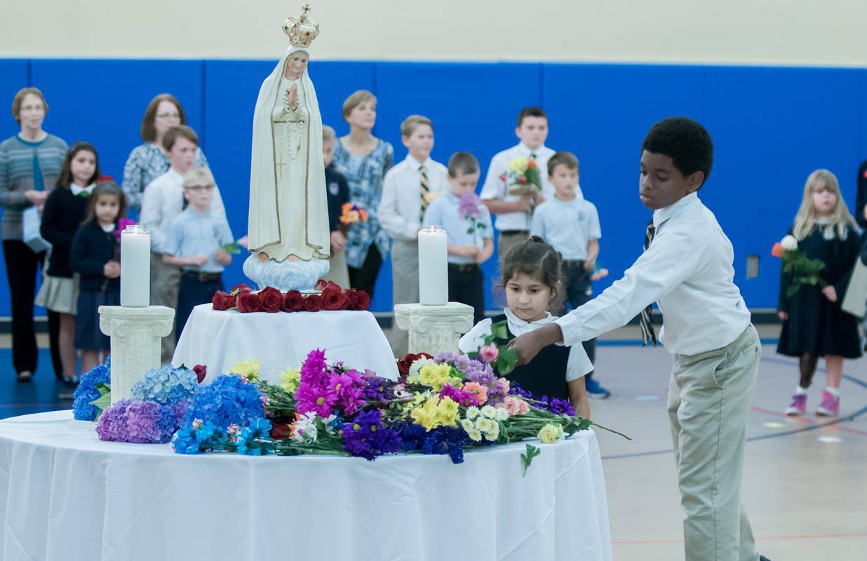 Students in all eight grades at Sacred Heart School prayed a “living rosary and laid flowers at the foot of a statue of Mary. Photo by Bill Washington, Catholic News Herald