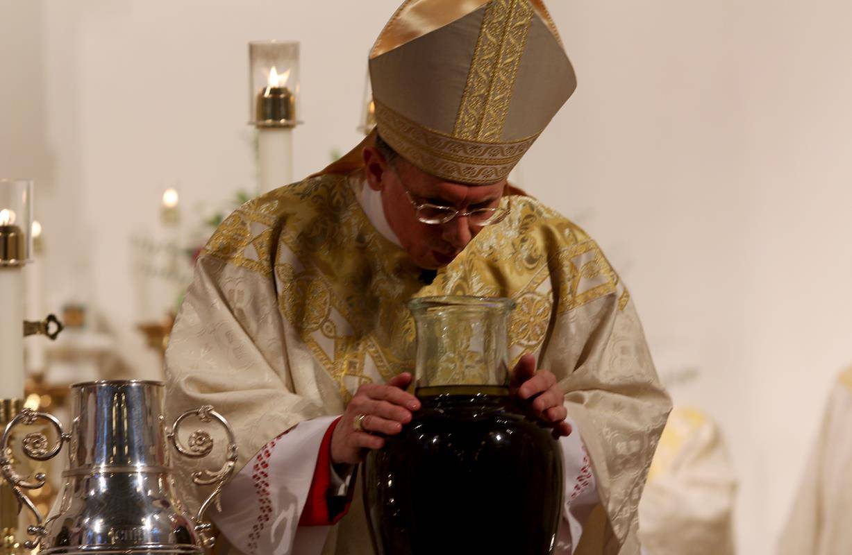 Bishop Jugis blesses the sacred chrism with prayers. blowing into the vessels to symbolize the coming of the Holy Spirit.
