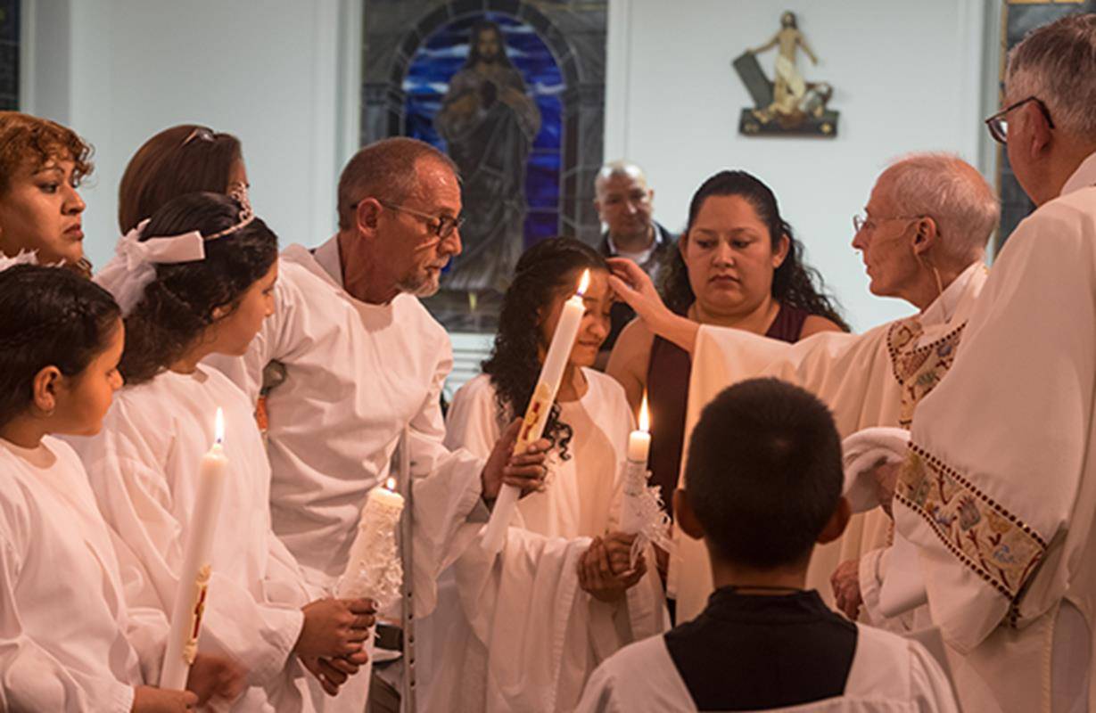 Administering the sacraments of initiation during the Easter Vigil at Our Lady of the Highways Church in Thomasville (Photo by Joe Thornton)
