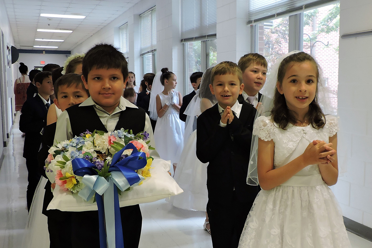 St. Mark School’s May Crowning Ceremony took place May 16, beginning with an all-school Mass offered by Father Brian Becker, parochial vicar at St. Mark Church. Dressed in their first Holy Communion attire, the second-graders led a rosary procession from