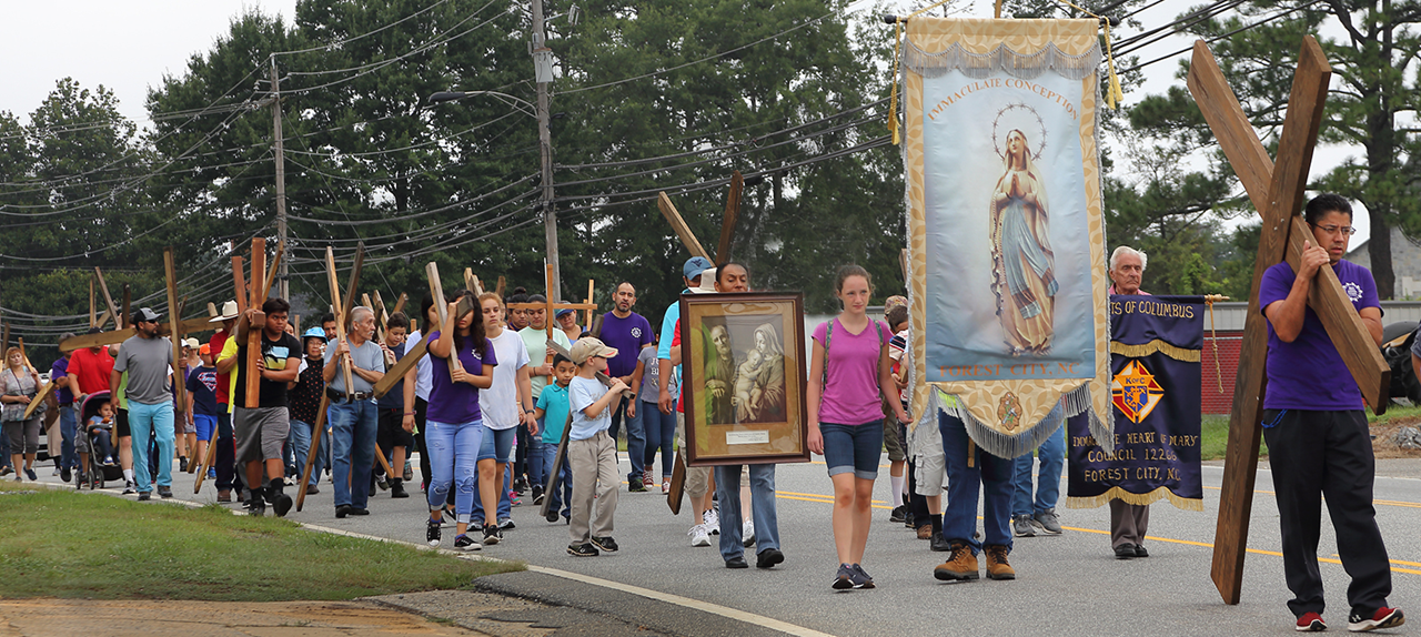Banners are carried in the procession. The walk began at Immaculate Conception Church, with Father Herbert Burke, pastor carrying the Blessed Sacrament. 