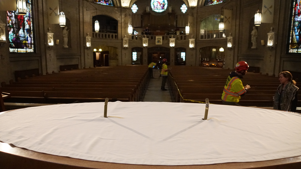 Technicians survey the interior of the basilica, including the altar area.