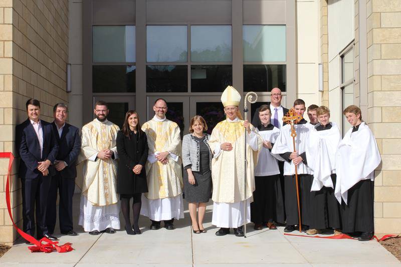 Emmett Sapp, Atnony Morlando, Father Paul McNulty,Assistant Principal Marissa Vandenberg, Father John Putnam, Dr. Janice Ritter, Bishop Peter Jugis, Prinicpal Dr. Carl Semmler and the CTKHS altar servers pose for a photo after the ribbon cutting Dec. 6. 