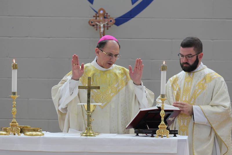 Father Paul McNulty, CTKHS chaplain, assists at Mass.