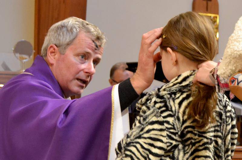 KERNERSVILLE — Father Paul Dechant, OSFS, distributes ashes to parishioners at Holy Cross Church March 6. (Paul Doize, correspondent)