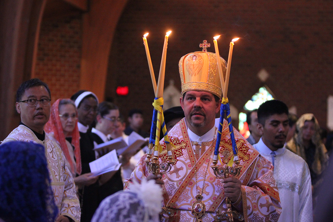 Bishop Bohdan Danylo, head of the Eparchy of Saint Josaphat of Parma, Ohio, blesses with the trikirion and dikirion in the form of a cross, to the east, the west, the south and the north, at the start of the Pontifical Divine Liturgy June 16.