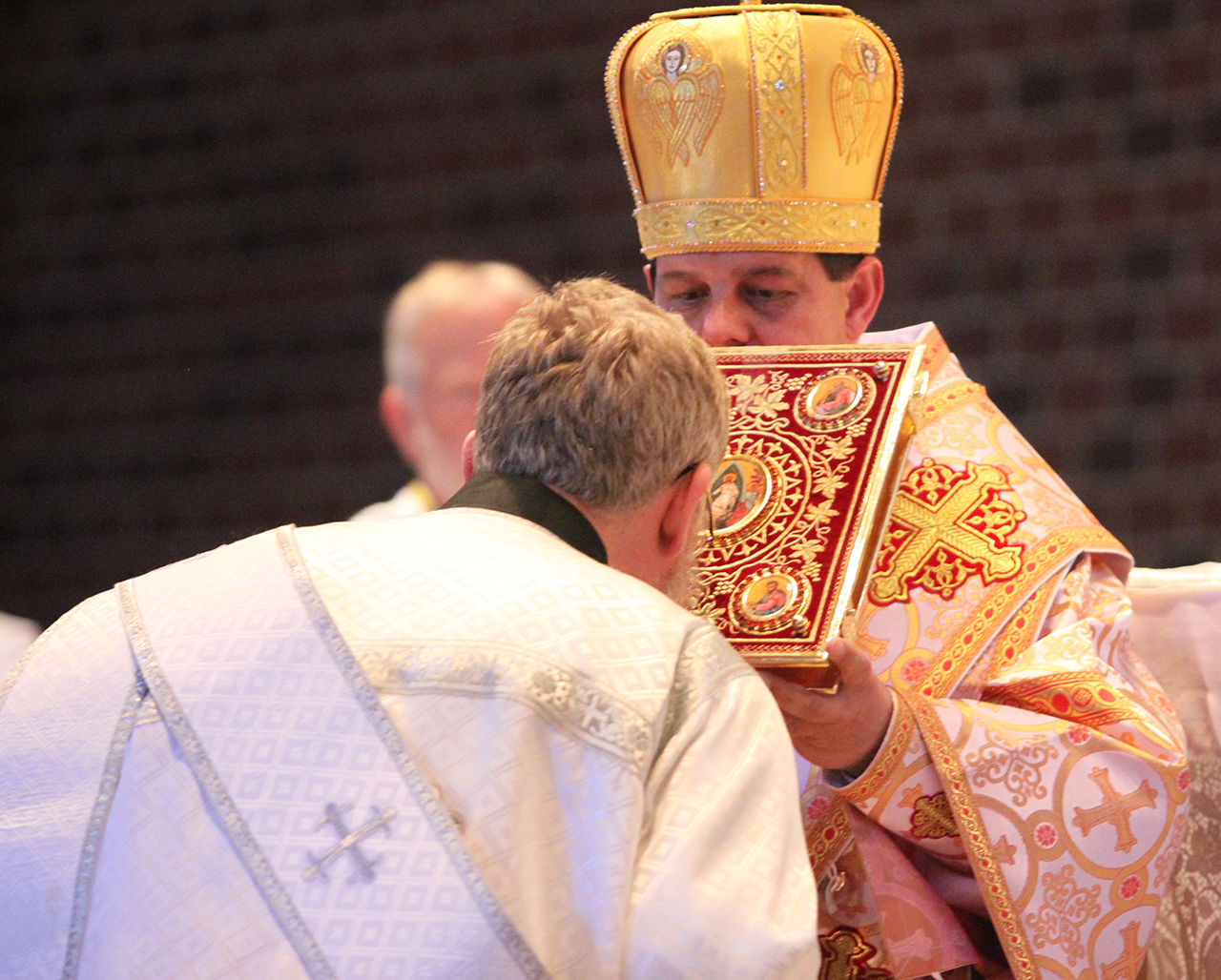 Kevin Bezner reverences the Book of the Gospels, held by Bishop Bohdan, during his ordination to the priesthood.