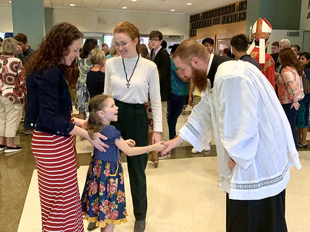 The school’s newest chaplain, Father Noah Carter, greets a student after Mass Aug. 28. (Photo provid-ed by Barbara Markun)