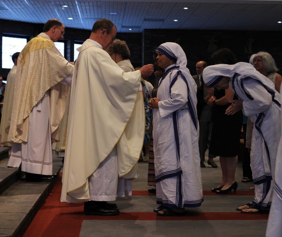 The local Missionaries of Charity, who serve in east Charlotte, near Our Lady of the Assumption Church, receive Communion from Monsignor John McSweeney, pastor of St. Matthew Church in Charlotte