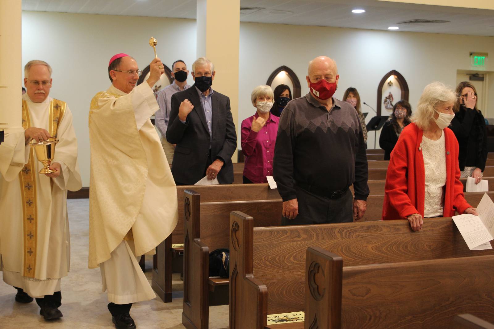 Bishop Peter Jugis, assisted by Deacon John Harrison, blesses the faithful during the new chapel dedication Jan. 27 at Holy Family Church in Clemmons.