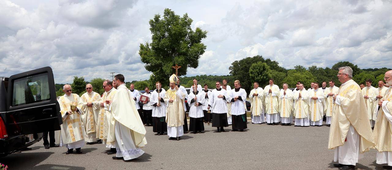 Clergy watch as the casket is placed in the hearse to go to Belmont Abbey Cemetery.