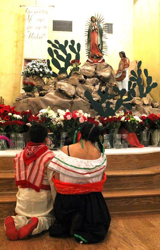 Two Monroe parishioners kneel in prayer before the image of Our Lady of Guadalupe. (Photo by SueAnn Howell)