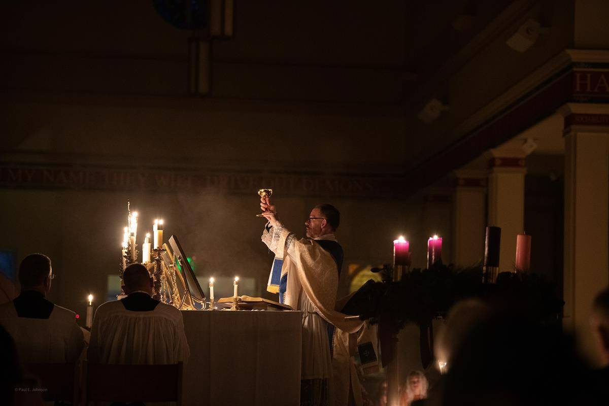 Father John Putnam, pastor, holds aloft the chalice containing the Precious Blood during the first Rorate Mass celebrated at St. Mark Church in Huntersville Dec. 11. More than 600 people attended the special liturgy. (Photo by Amy Burger)