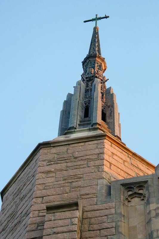 The soaring spire of the church pierces the clear blue sky.