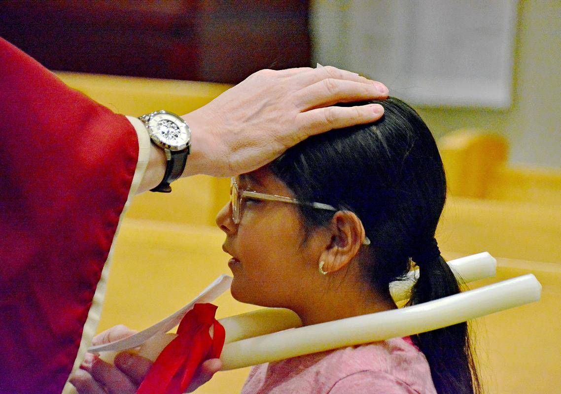 Father Eric Kowalski blesses his parishioners’ throats on the Feb. 3 feast of St. Blaise.