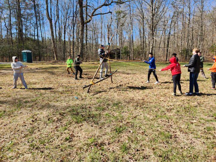 Scouts lash together poles to form a Trinity Triangle. (Photo by Joe Ordoyne)