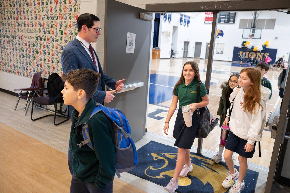 Dr. Gregory Monroe, Superintendent of Catholic Schools, greets students at St. Mark School in Huntersville for the start of Catholic Schools Week. 