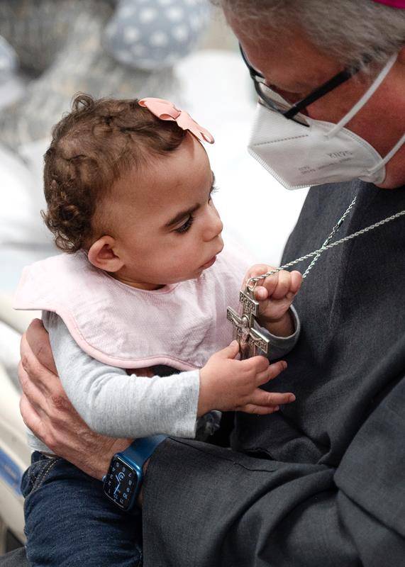Bishop-Elect Michael Martin, OFM Conv., holds Holy Angels' youngest resident during his visit. Belmont-based Holy Angels cares for children and adults with intellectual developmental disabilities and delicate medical conditions.