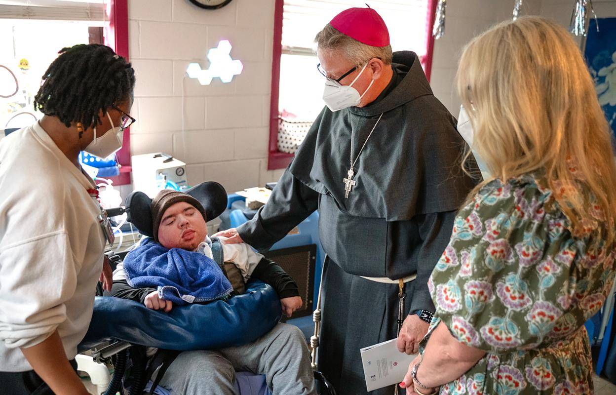 Charlotte Bishop-Elect Michael Martin, OFM Conv., greets Holy Angels resident Zach during an April 9 visit to the Diocese of Charlotte following the Vatican's announcement that he will succeed Bishop Peter Jugis.
