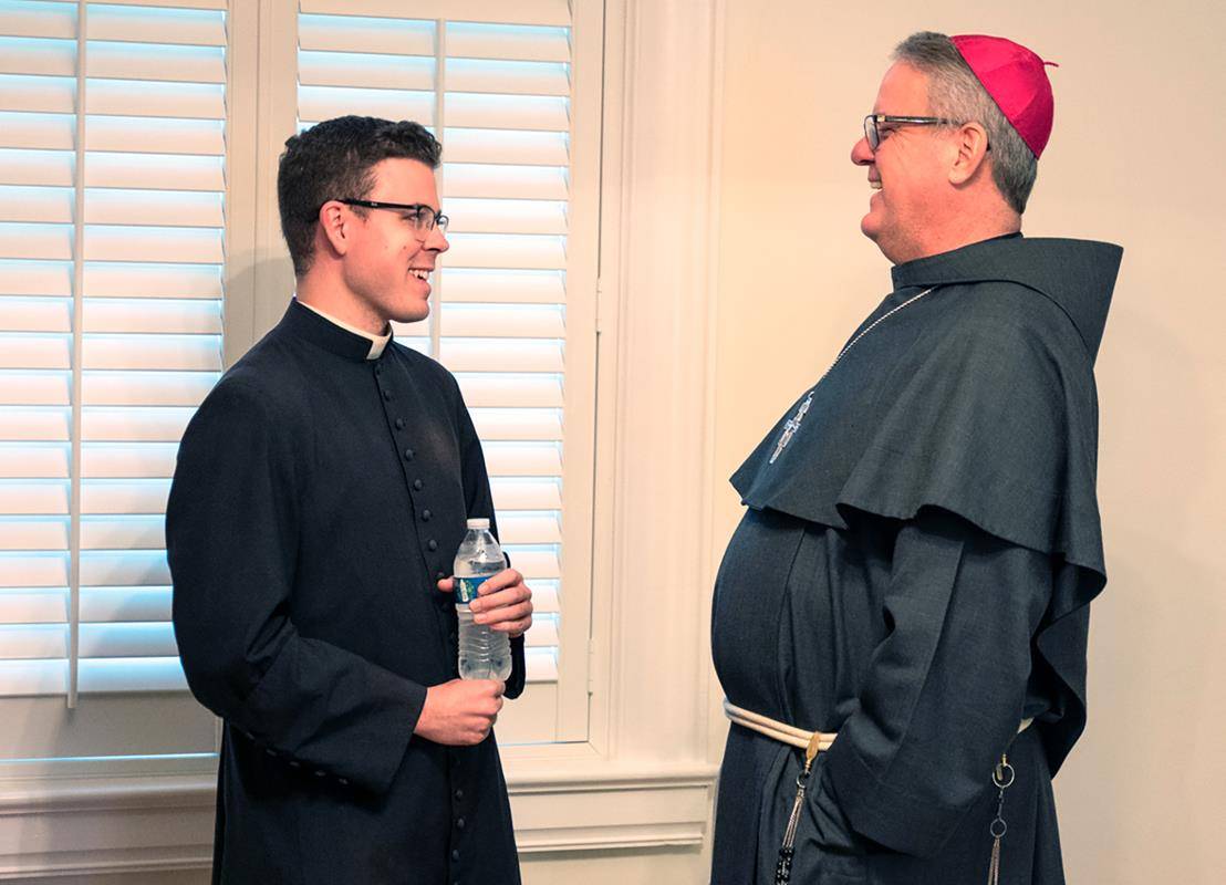 Charlotte Bishop-Elect Michael Martin, OFM Conv., speaks April 9 to Father Christopher Brock, one of the Diocese of Charlotte's newest priests.