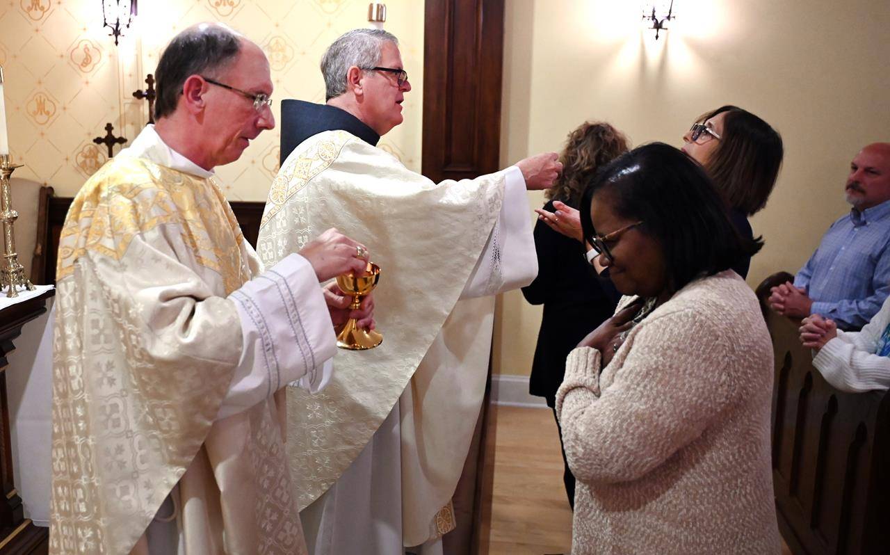 Charlotte Bishop-Elect Michael Martin, OFM Conv., and retiring Bishop Peter Jugis distribute Communion during a Mass in the Diocese of Charlotte Pastoral Center chapel April 9, before the bishop-elect embarked on a series of visits around Charlotte.