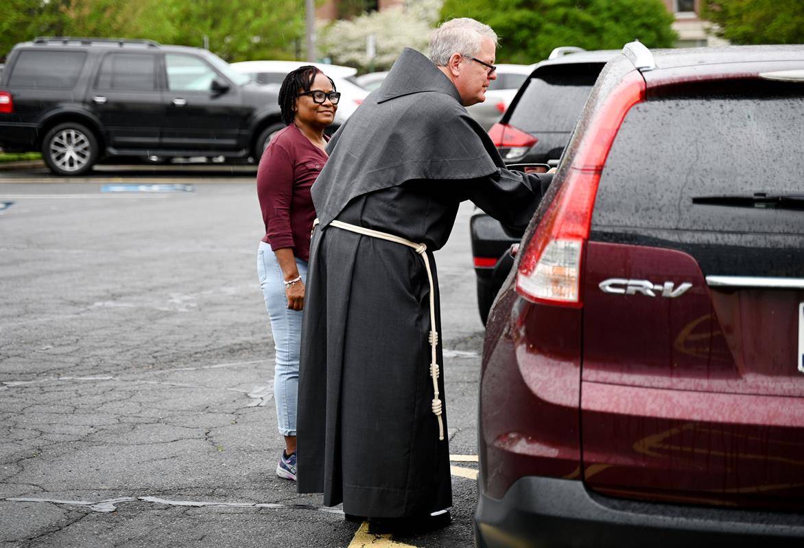 Bishop-Elect Michael Martin, OFM Conv., greets and prays with a family who came through the food distribution line at Catholic Charities' food pantry in the Diocese of Charlotte Pastoral Center April 9.