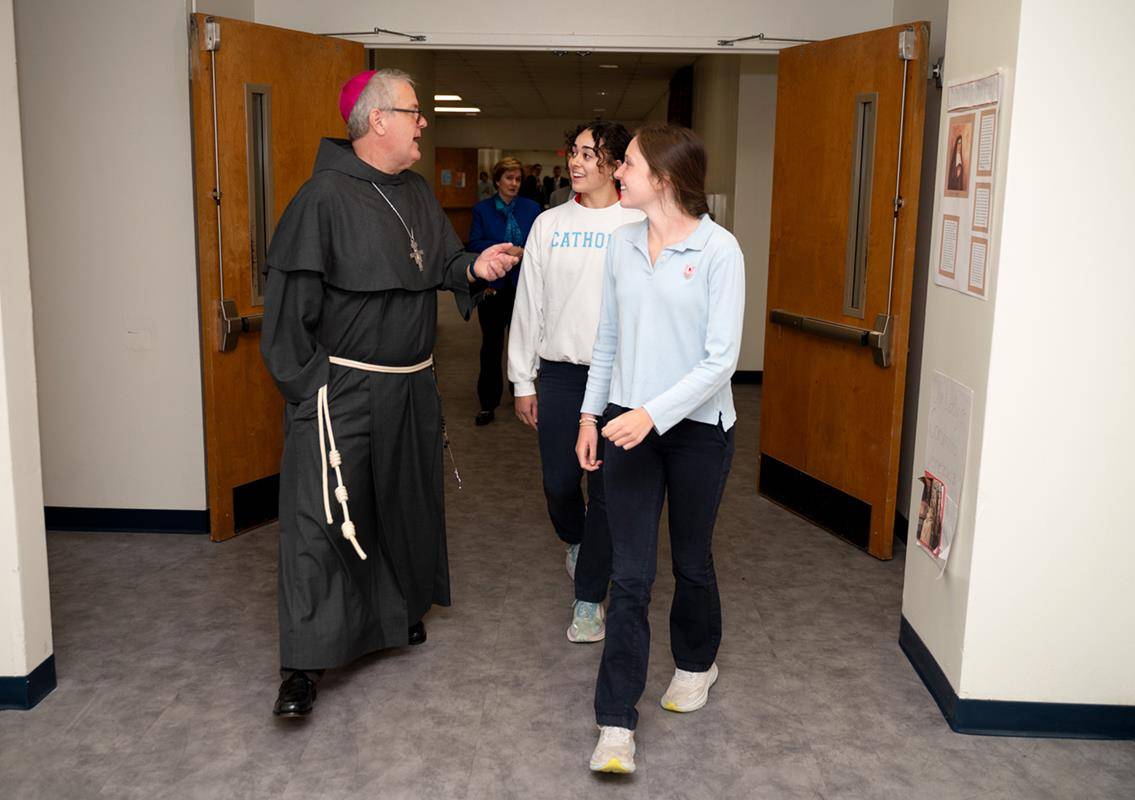 Bishop-Elect Michael Martin, OFM Conv., tours Charlotte Catholic High School April 9 with students Natalie Dominguez (left) and Madeline Lewis, during his first day visiting the Diocese of Charlotte.