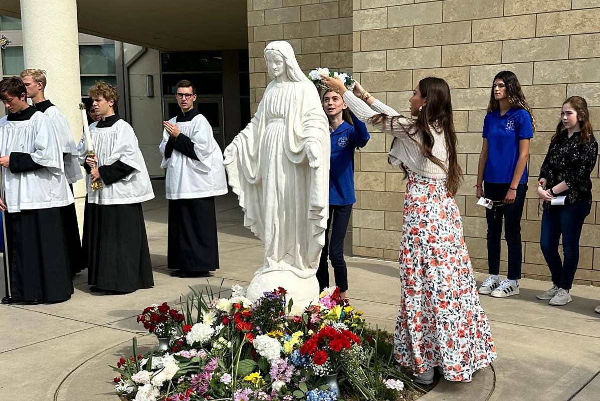 In keeping with school tradition, the oldest and youngest Christ the King female students have the honor of placing the crown of flowers on Mary’s head.