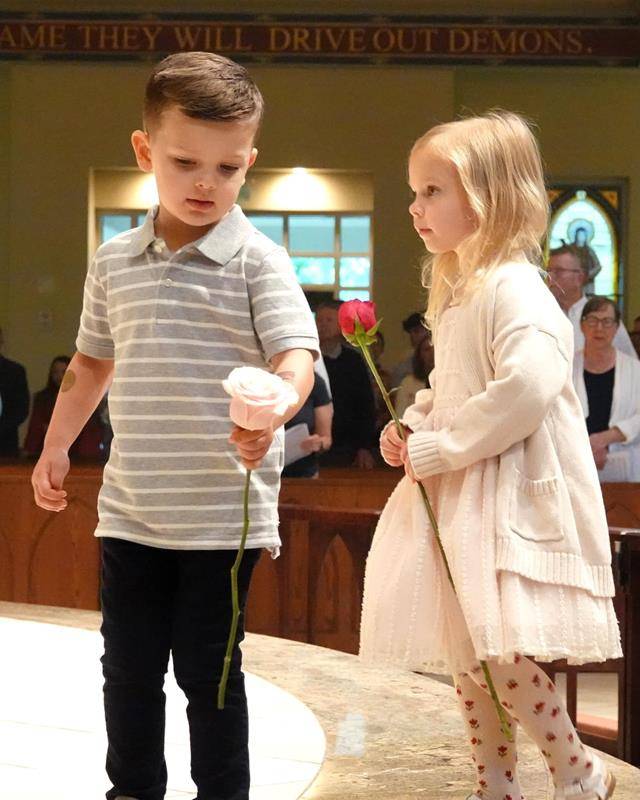 Children place flowers at Mary's feet at St. Mark Church