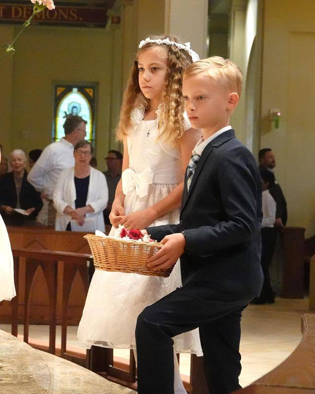 Irene Shingledecker and Brian Button, who recently received their First Holy Communion at St. Mark Church, had the honor of carrying the crown and placing it on Mary’s head after a procession of children placed flowers at her feet. 