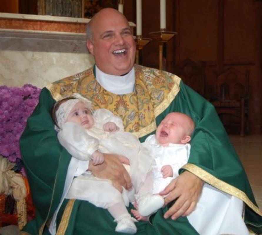 Monsignor Marcaccio loved baptisms even if the children weren’t always happy. He poses here with two of the church’s newest members.