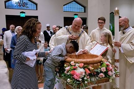 Msgr. Marcaccio baptizes a young parishioner during the Easter Vigil Mass in 2019. (Photo by Mary Ann Luedtke)