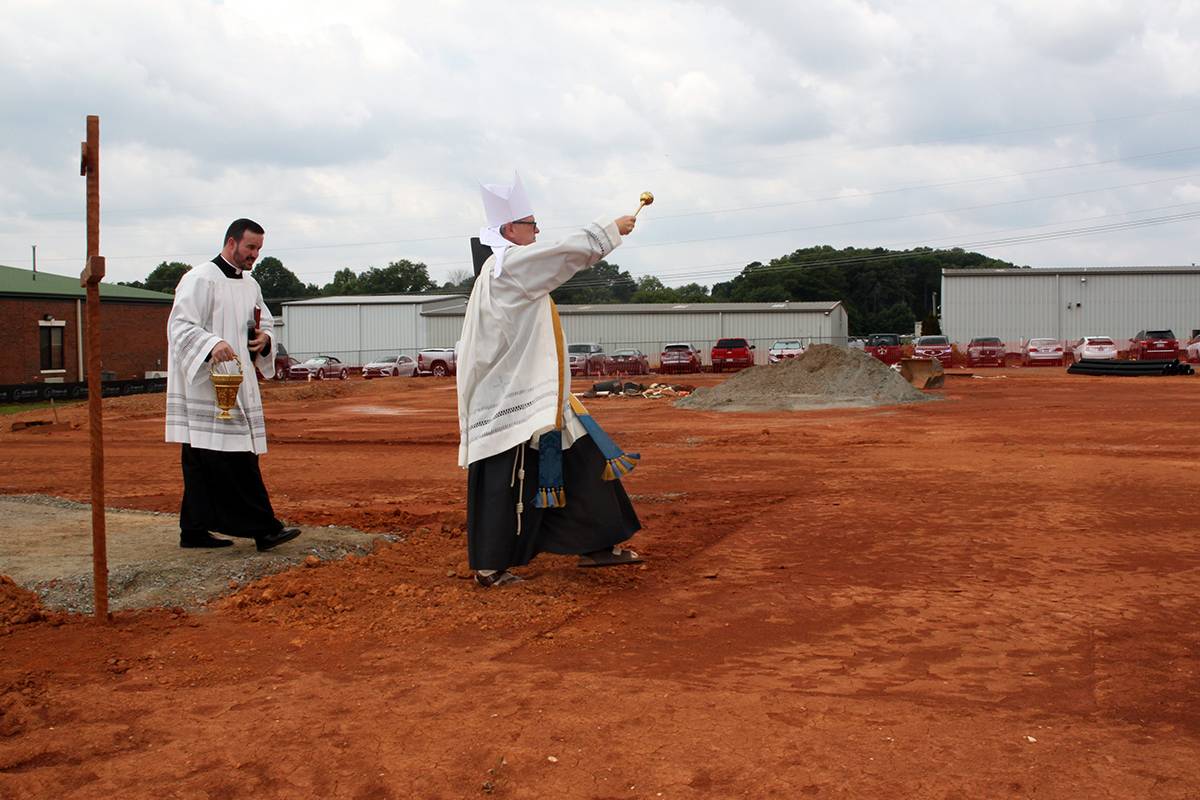 Bishop Martin, followed by Father Miguel Sanchez, blesses the site of the future church with holy water.