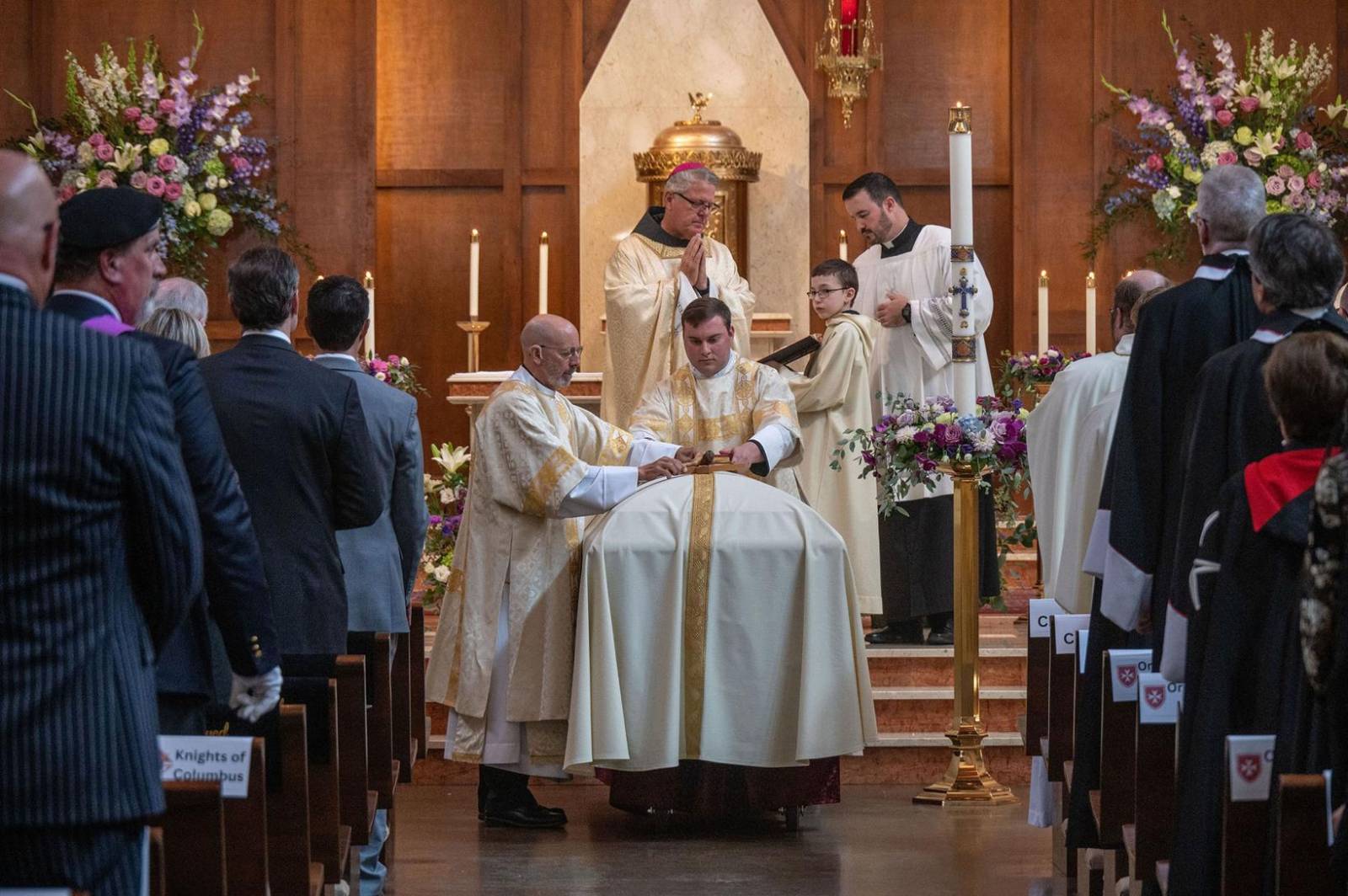 A crucifix and Bible are placed atop the casket, symbols of the Christian life.