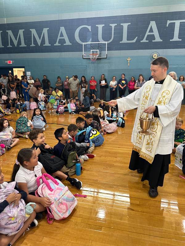 The annual “Blessing of the Backpacks” marked the start of the first day of school at Immaculata Catholic School with Father Andres Gutierrez dispersing holy water in the gym during morning assembly Aug. 19. 