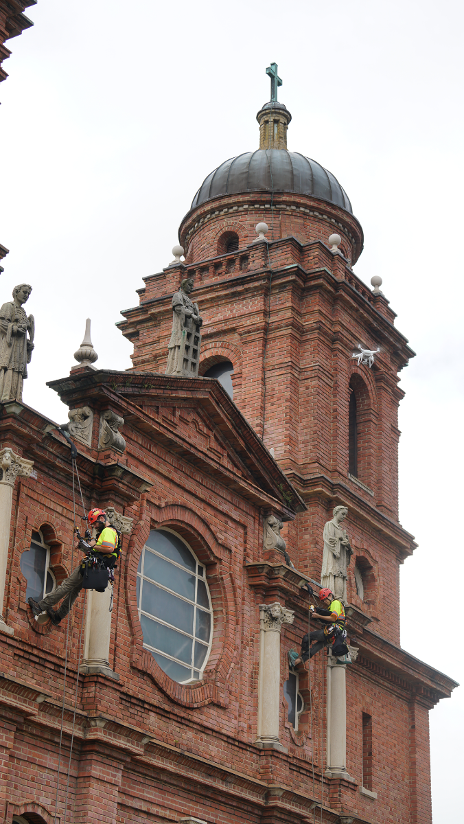 A drone flies above Vertical Access rappelers as St. Lawrence Basilica gets a thorough evaluation inside and out, the first step in planning a restoration of the century-old church in downtown Asheville. 