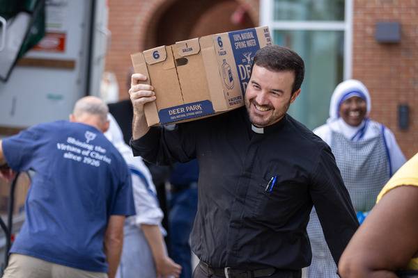 Father Miguel Sanchez, the bishop's priest-secretary, gladly joined in the work to unload the latest truck of supplies. (Gabriel Swinney)