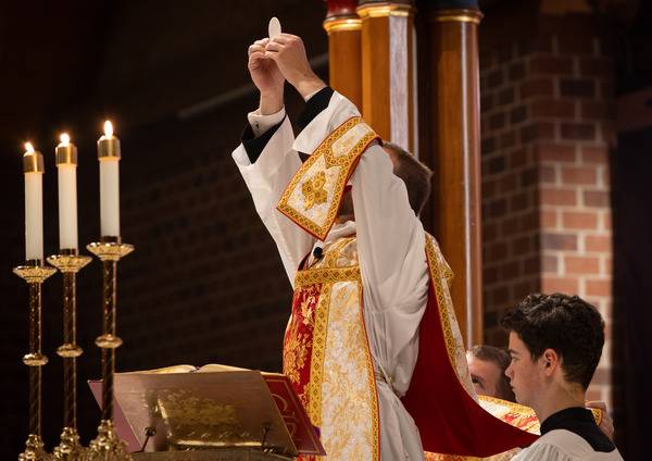 Father Matthew Harrison elevates the consecrated Host during Holy Thursday Mass of the Lord’s Supper at St. Thomas Aquinas Church in Charlotte. (Photo by Edward Chaplinsky Jr.)