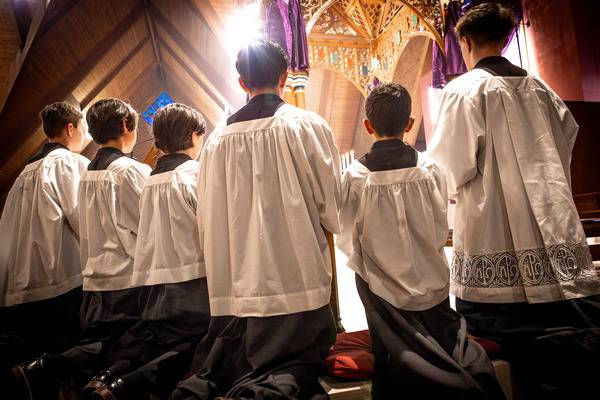 Altar servers kneel in front of the altar during Holy Thursday Mass of the Lord’s Supper at St. Thomas Aquinas Church in Charlotte. (Photo by Edward Chaplinsky Jr.)