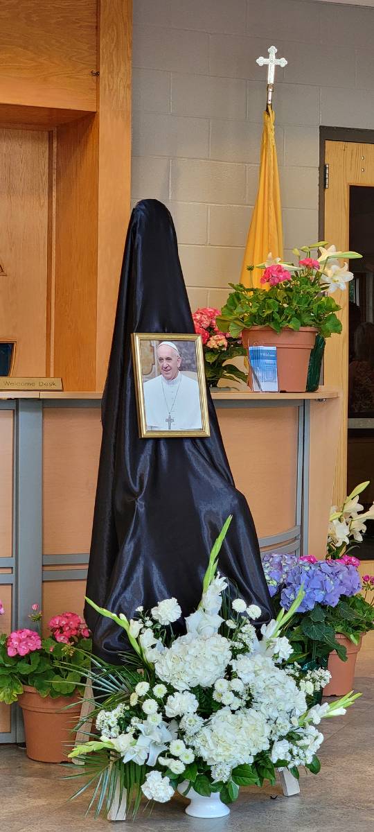 Portraits of the pope, which normally hang in the entryways of Catholic churches, were taken down, placed near the altar, and draped with black or purple bunting as a sign of mourning for the late pontiff. This one is from St. Gabriel Church in Charlotte.