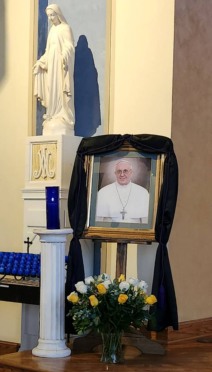 Portraits of the pope, which normally hang in the entryways of Catholic churches, were taken down, placed near the altar, and draped with black or purple bunting as a sign of mourning for the late pontiff. This one is from St. Patrick Cathedral in Charlot