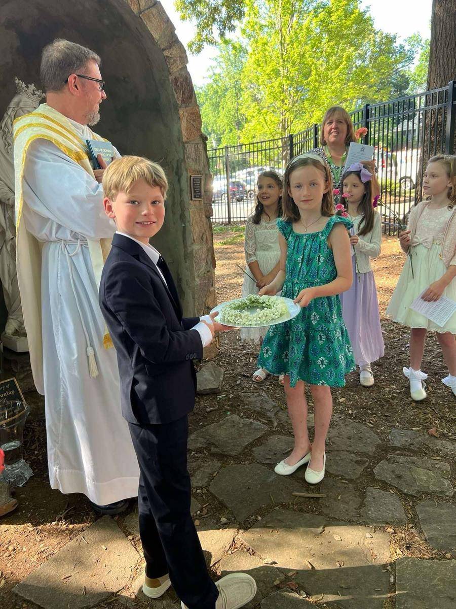 Second grade First Communicants lead processions during Mass and then afterwards to crown The Blessed Virgin Mary statue in our Marian Grotto. 
