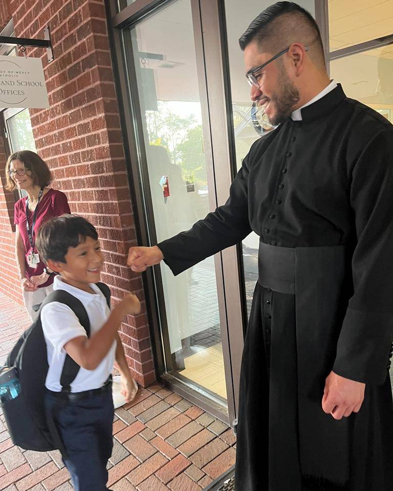 Father Cory Catron and Father José Palma welcome students to Our Lady of Mercy School in Winston-Salem. 